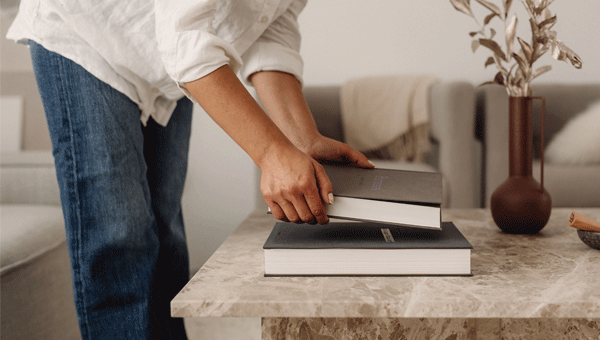Person placerar coffee table books på ett soffbord